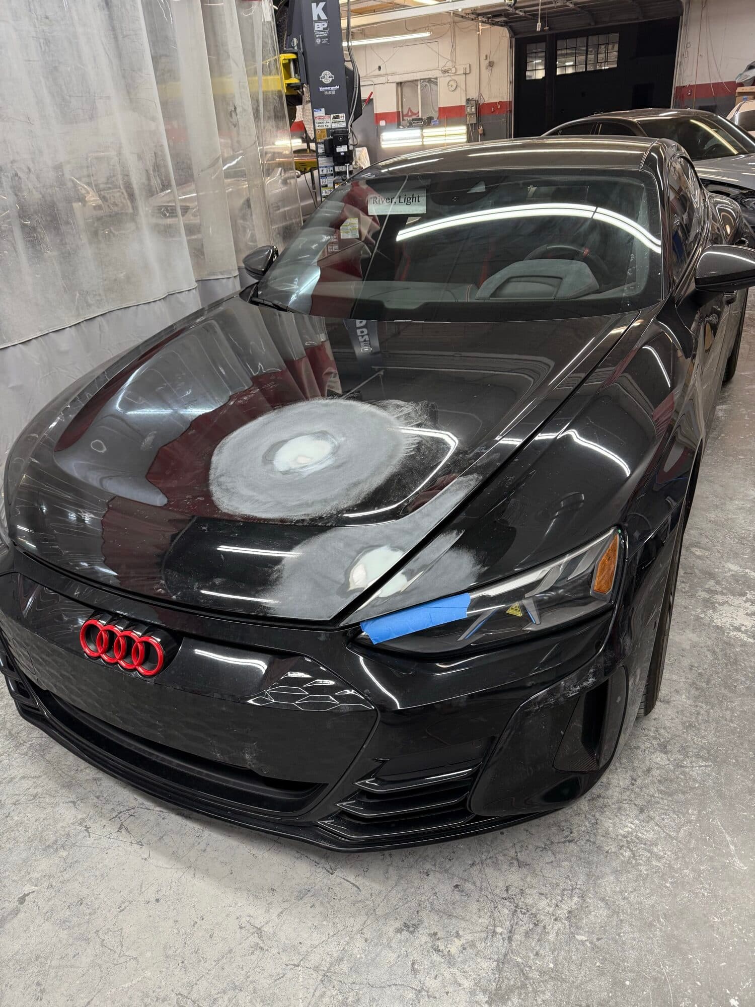 Black Audi e-tron GT with collision damage on the hood at Alpina Auto Body, Audi collision repair shop in Southeast Portland, Oregon