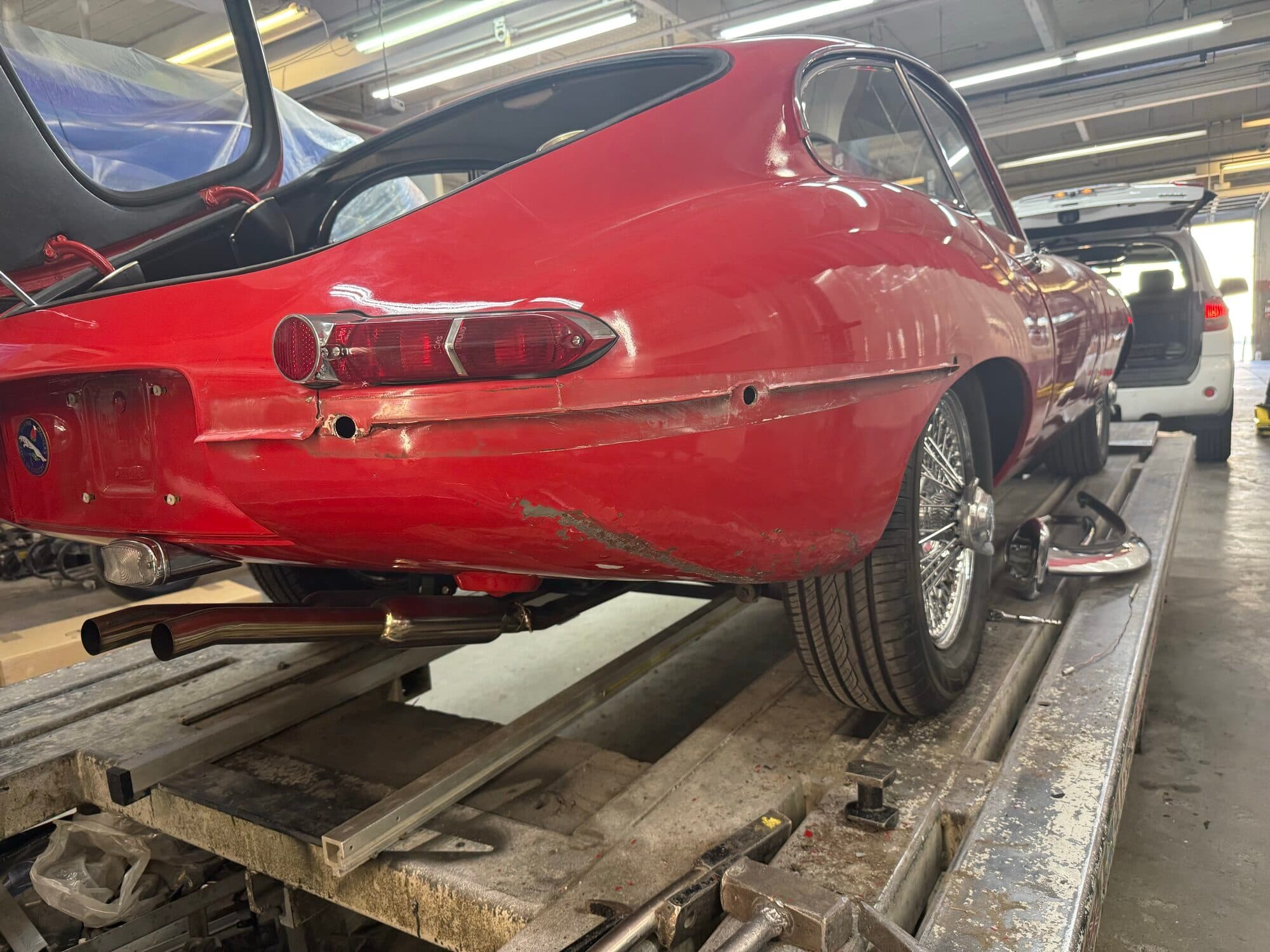 Red classic Jaguar E-Type on the rack at Alpina Auto Body, classic car restoration and body shop in Southeast Portland, Oregon