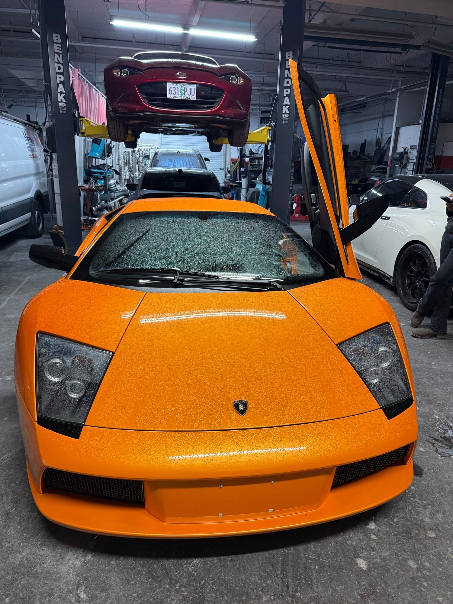 Orange Lamborghini Aventador with the scissor door up at Alpina Auto Body, Lamborghini repair and body shop in Southeast Portland, Oregon