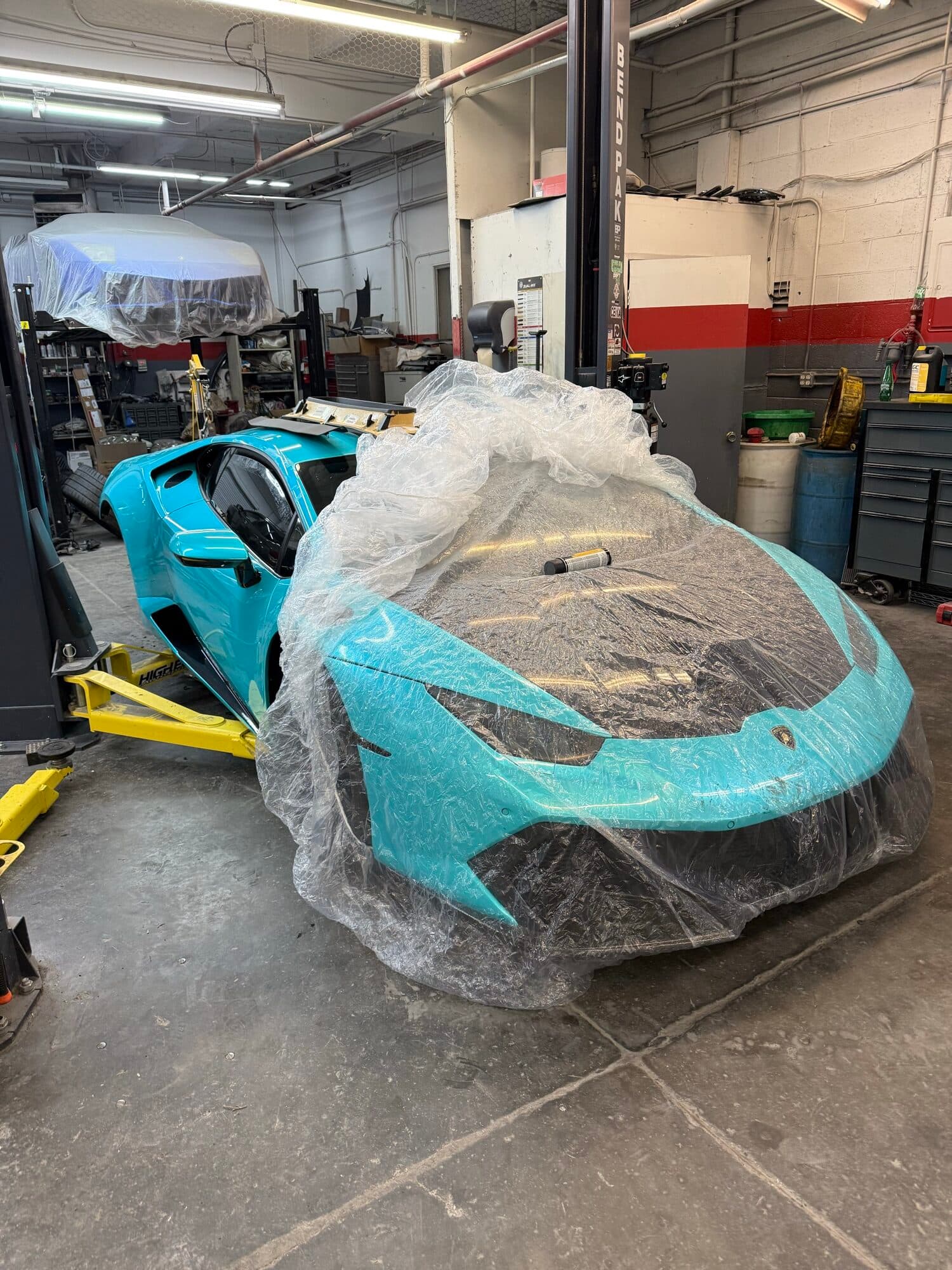 A teal Lamborghini Huracan with collision damage, disassembled at Alpina Auto Body, Portland